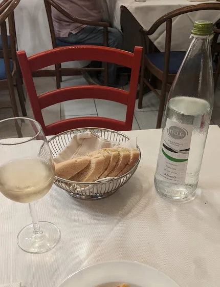 Set table with bread, glasses and a bottle in the trattoria dining room.