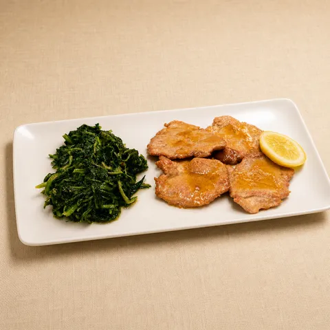 Lemon scaloppina and cooked greens on a rectangular plate.