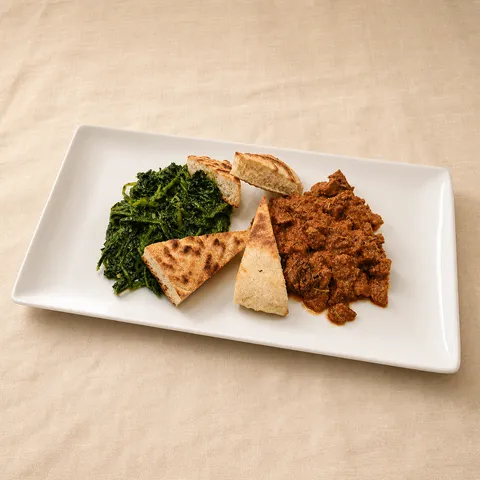 Wild boar bites with torta al testo and cooked greens on a rectangular plate.