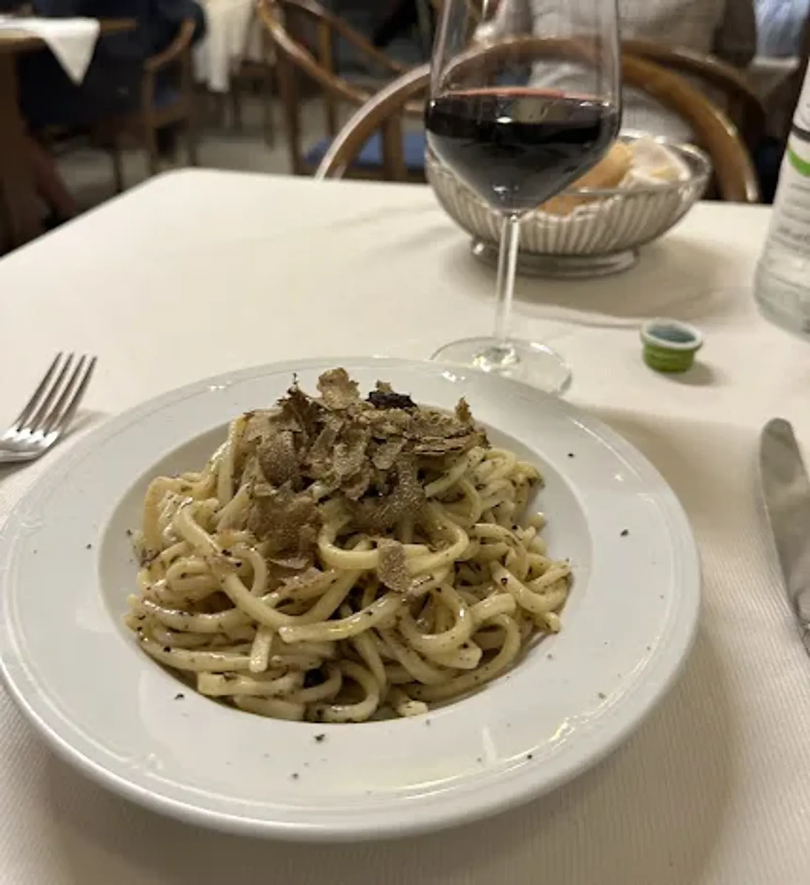 Pappardelle condite con tartufo fresco servite su un piatto bianco.